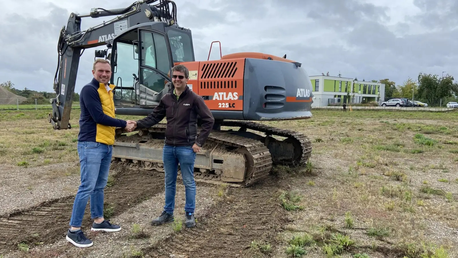 Handschlag vor dem soeben abgeladenen Bagger (noch ohne Schaufel): Hermann Schröder von der Schröder Holding GmbH (l.) und Christoph Schmidt von der Straßen- und Tiebau GmbH Osterfeld freuen sich über den Baubeginn. (Foto: taucha-kompakt.de)